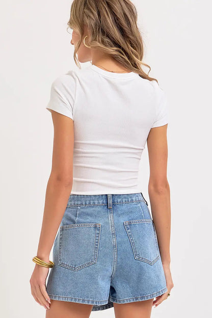 Person wearing a white t-shirt and denim shorts on a plain background