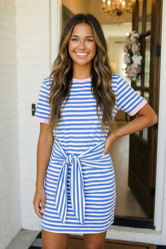 Woman wearing a blue and white striped dress standing indoors.