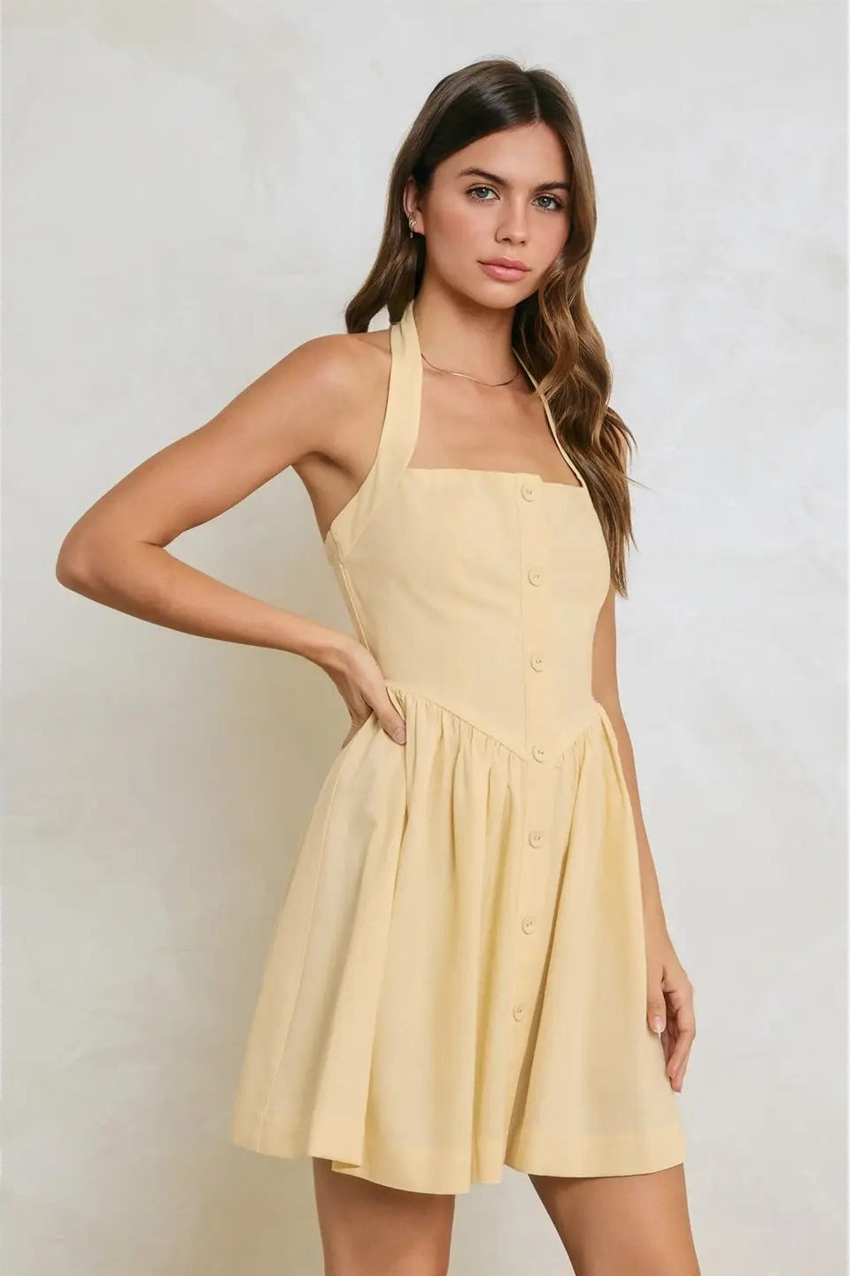 Woman wearing a yellow dress against a plain background