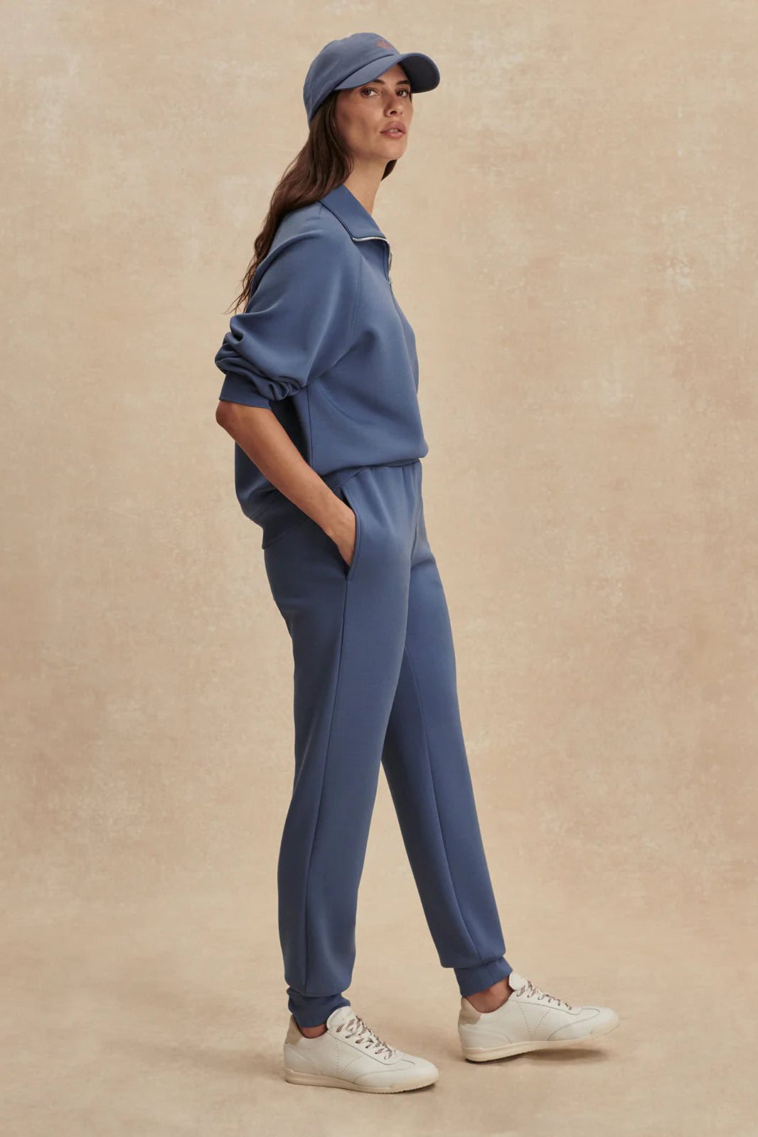 Woman wearing a blue outfit with a cap on a beige background