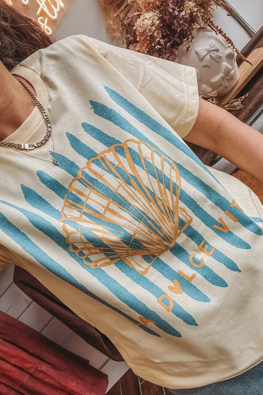 Person wearing a t-shirt with a shell design and 'Dulce Vita' text.