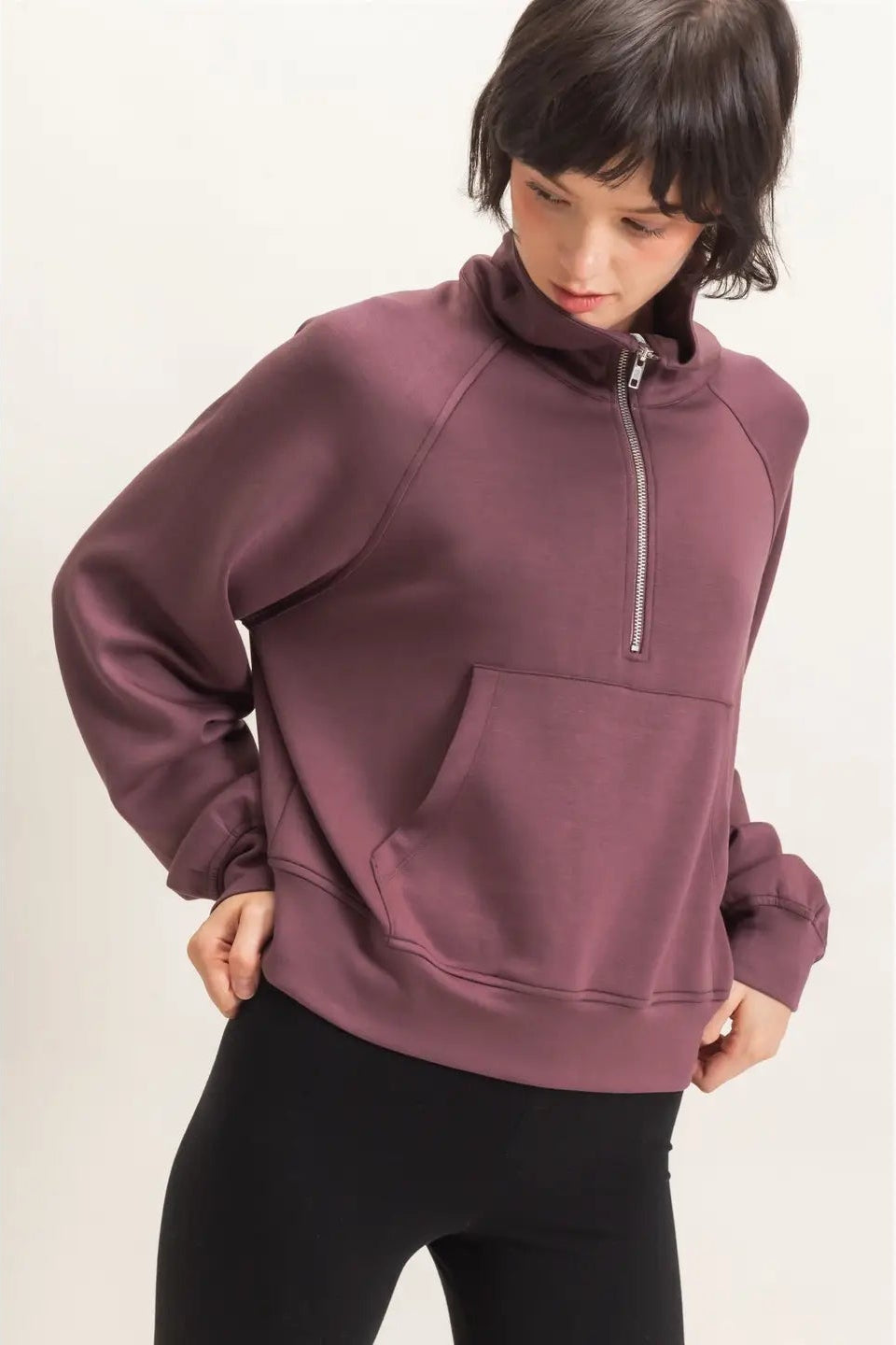 Person wearing a maroon hoodie with a zipper on a white background