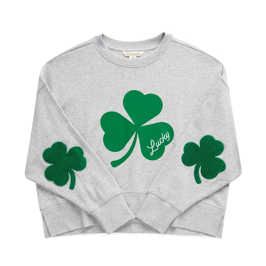 Gray sweatshirt with green shamrock designs on a white background