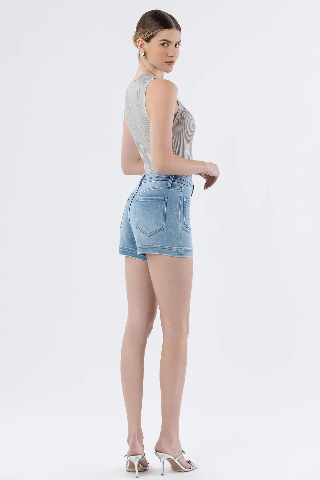 Woman wearing a sleeveless top and denim shorts on a white background