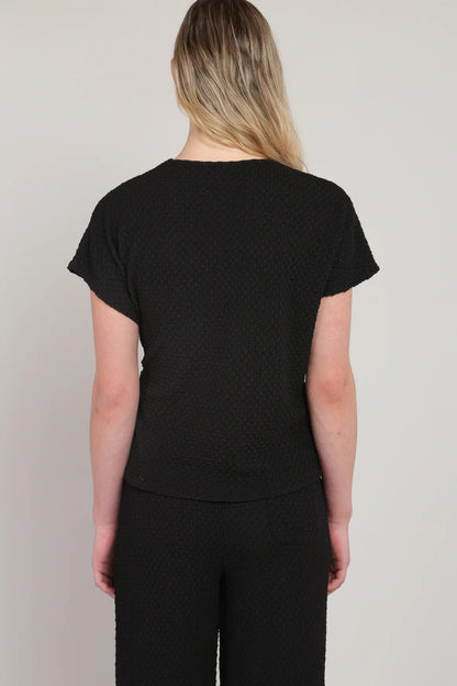 Person wearing a black t-shirt and pants on a plain background
