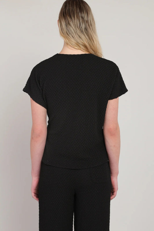 Person wearing a black t-shirt and pants on a plain background