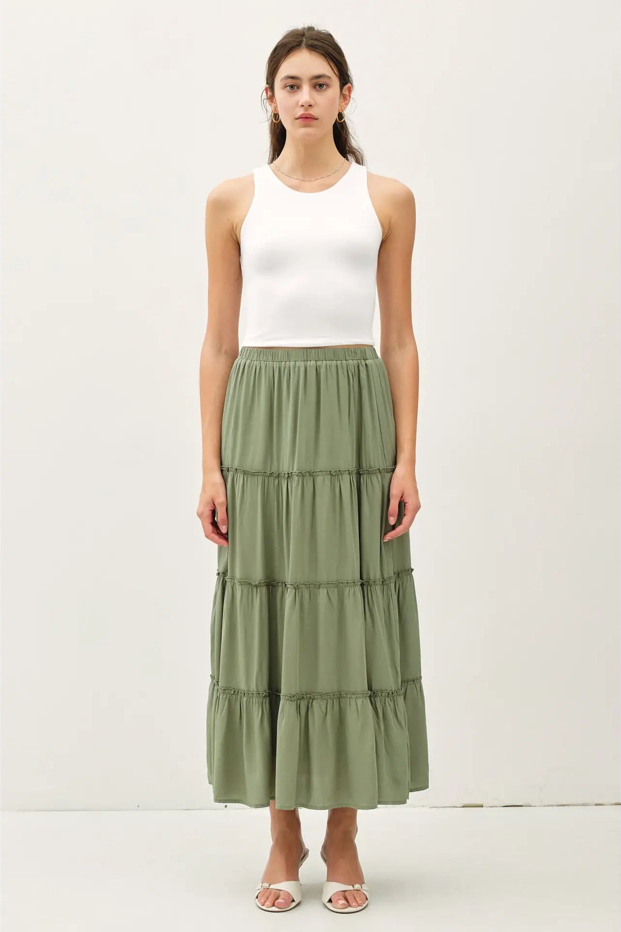 Woman wearing a white top and green tiered skirt on a white background