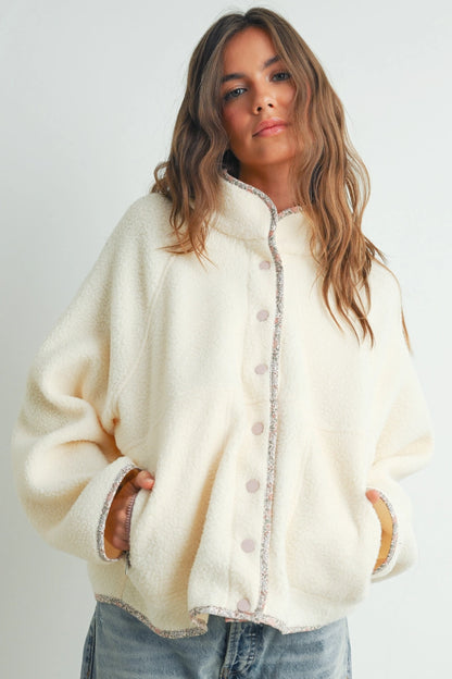 Woman wearing a cream-colored jacket with a plain background