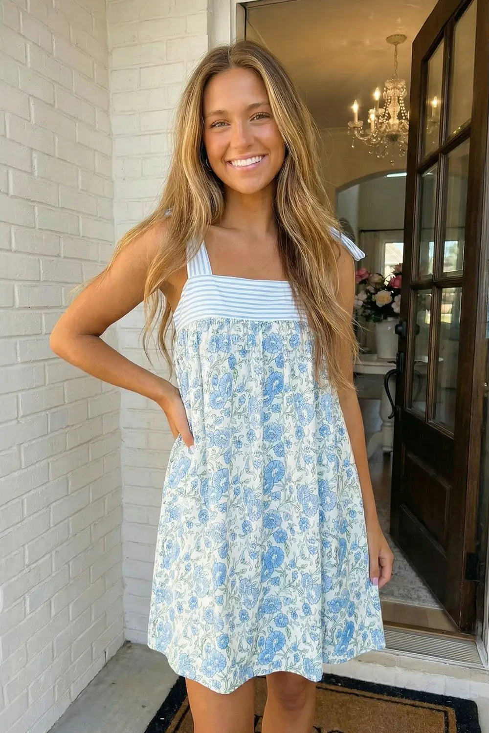 Woman wearing a blue floral dress standing in a home setting.