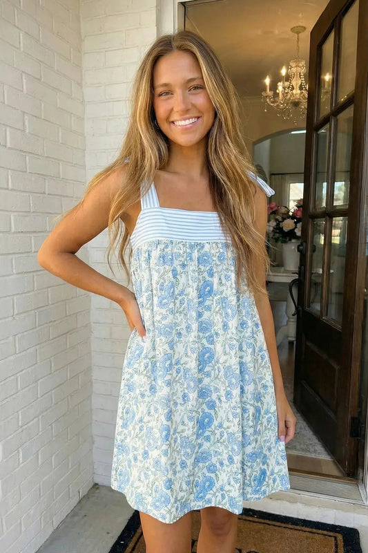 Woman wearing a blue floral dress standing in a home setting.