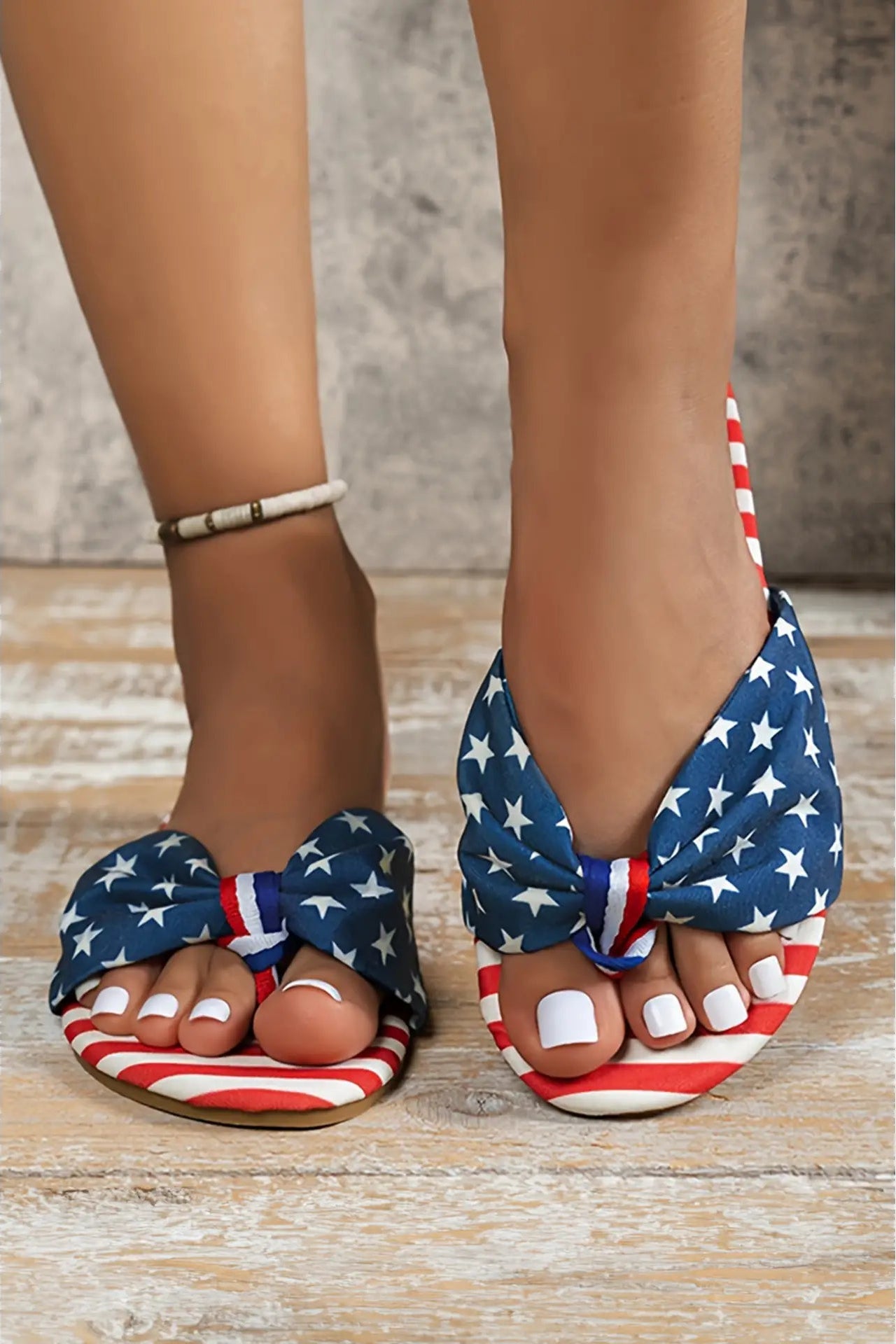 Flag-patterned sandals on feet with a neutral background