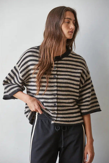 Woman wearing a black and beige striped sweater against a plain background