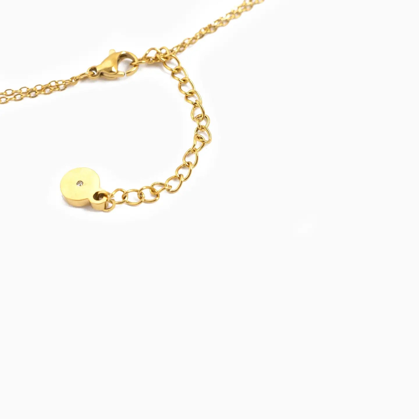 Gold necklace with a small round pendant on a white background