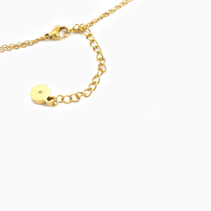 Gold necklace with a small round pendant on a white background