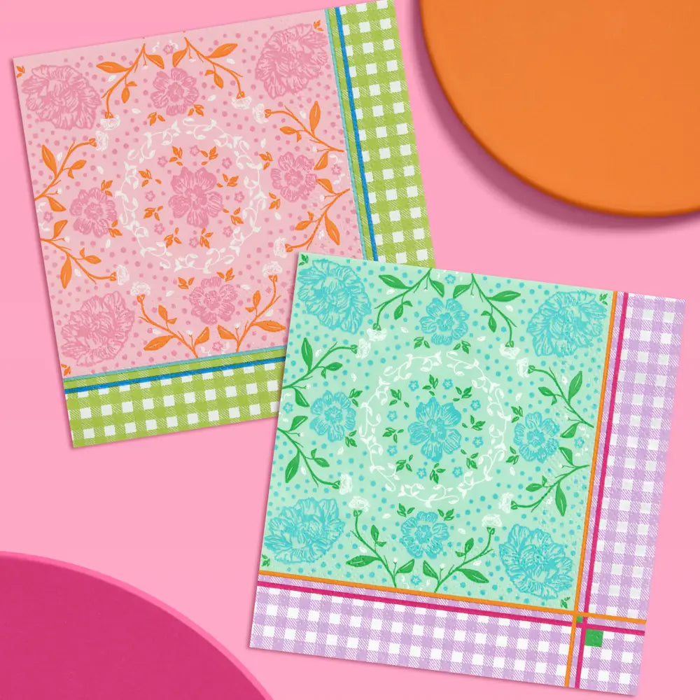 Two decorative paper napkins with floral and gingham patterns, arranged on a pink background with partial orange and magenta shapes.