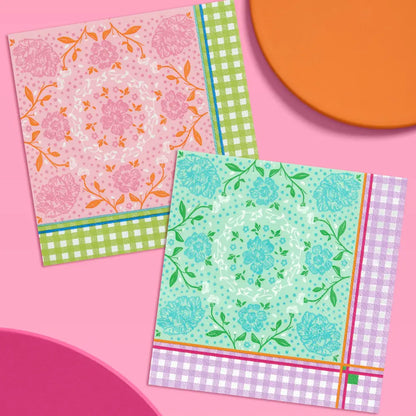 Two decorative paper napkins with floral and gingham patterns, arranged on a pink background with partial orange and magenta shapes.