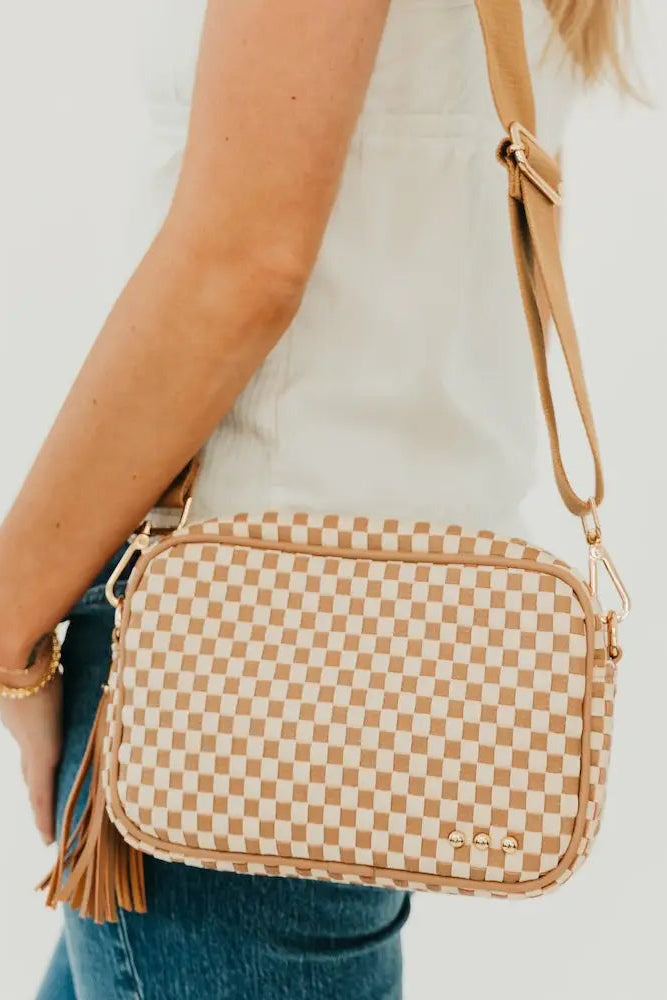 Person holding a checkered crossbody bag with a plain background
