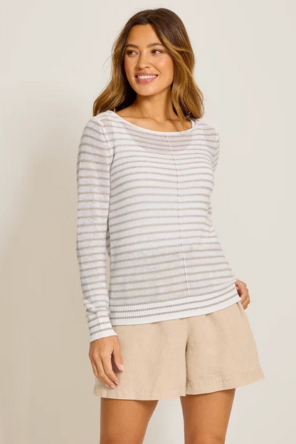 Woman wearing a striped long-sleeve top and beige shorts on a plain background