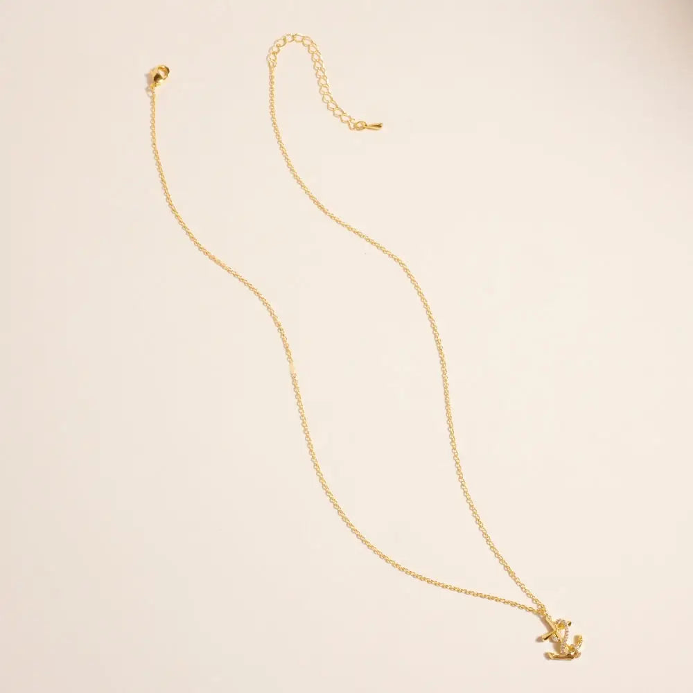 Gold necklace with a small pendant on a beige background