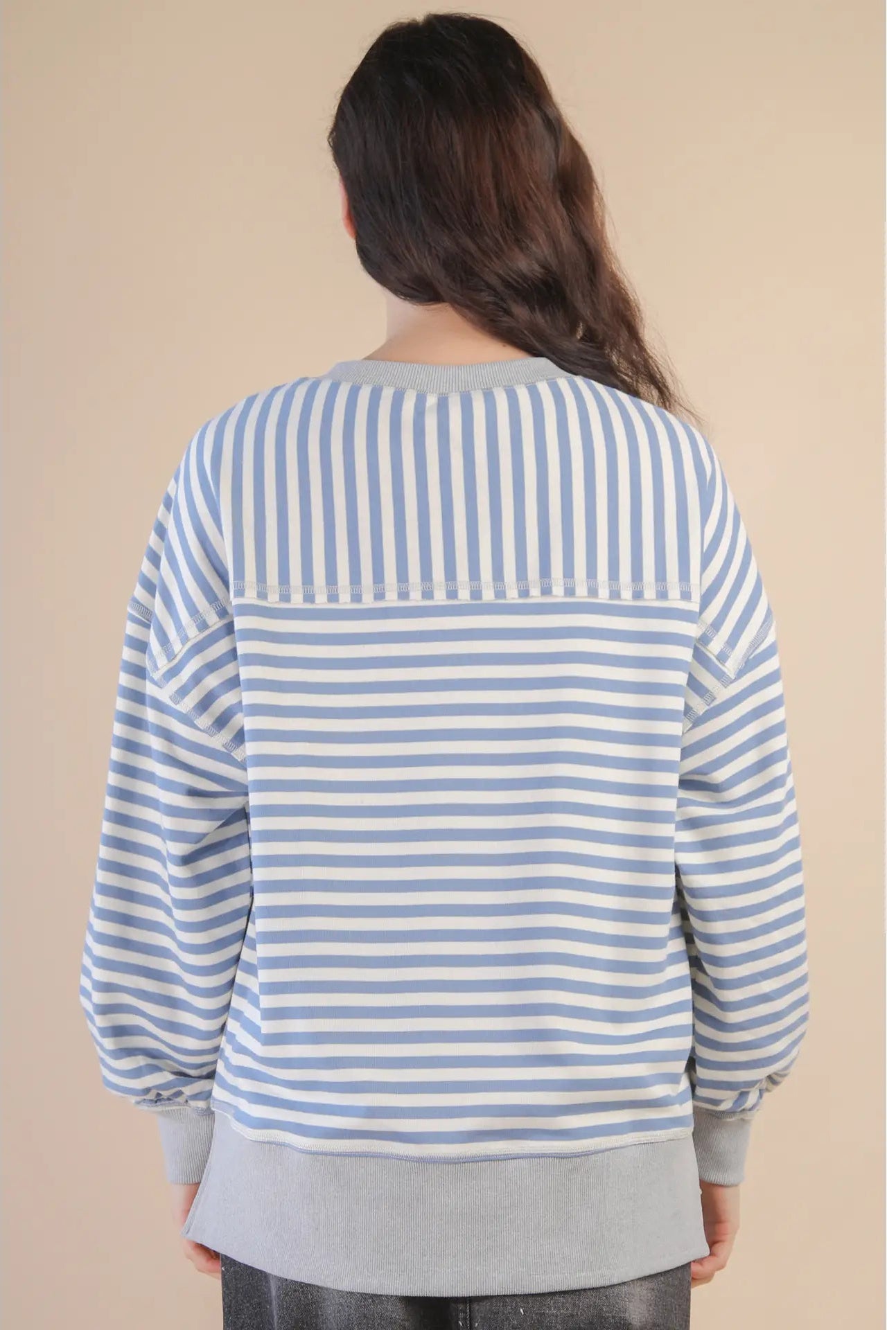Person wearing a blue and white striped shirt on a beige background