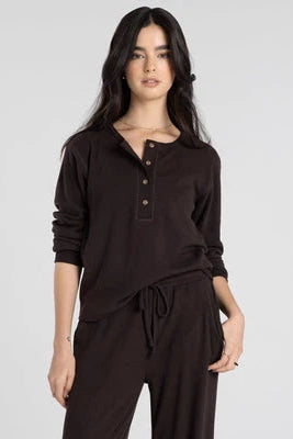 Woman wearing a brown long-sleeve top and pants on a white background