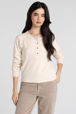 Woman wearing a beige long-sleeve shirt and beige pants on a white background