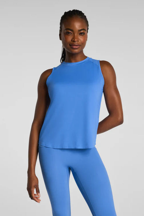 Woman wearing a blue sleeveless top and leggings on a light gray background