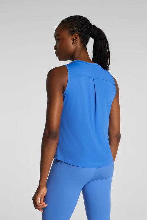 Person wearing a blue sleeveless top and leggings on a light gray background