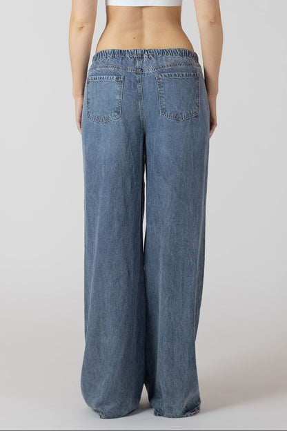 Blue wide-leg jeans worn by a person on a white background