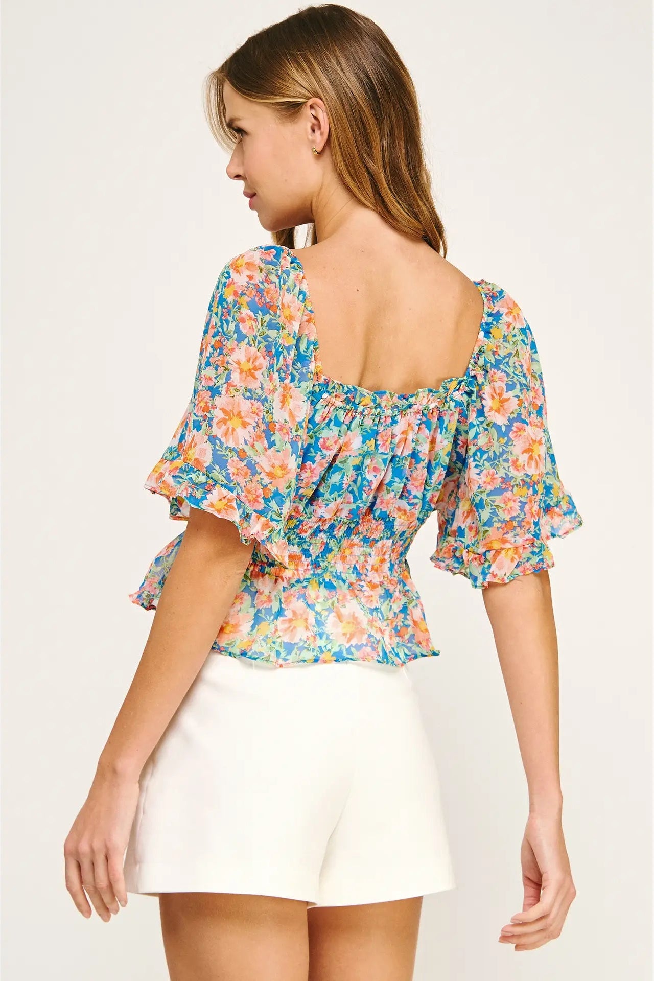 Woman wearing a colorful floral blouse with a plain background