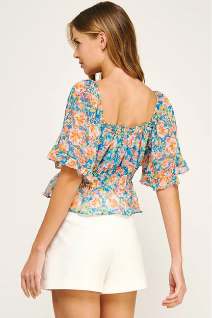 Woman wearing a colorful floral blouse with a plain background