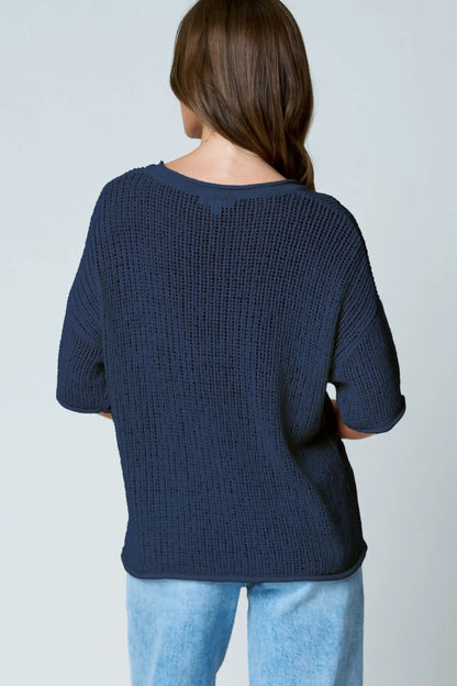 Person wearing a navy blue sweater and light blue jeans on a plain background