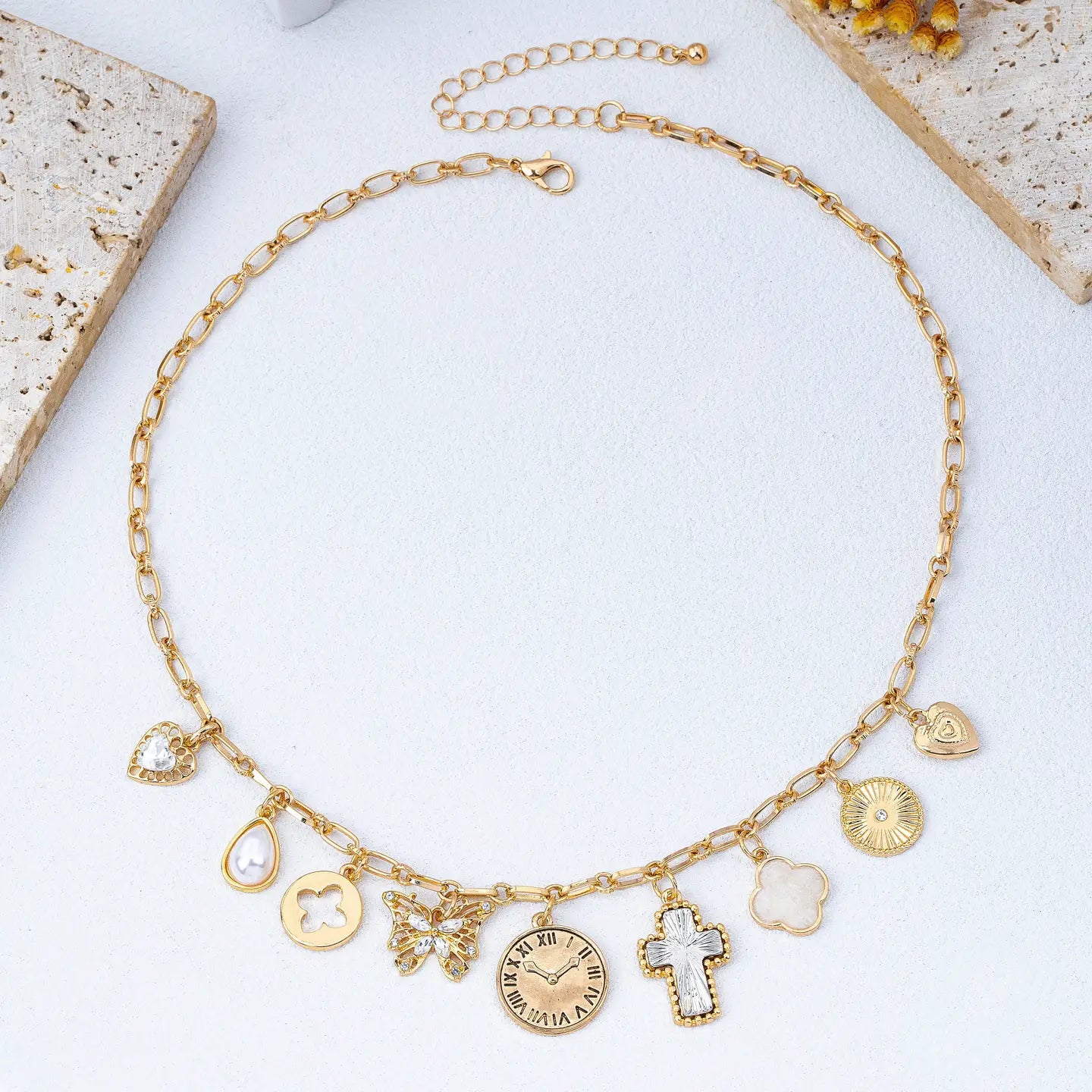 Gold necklace with various charms on a light background