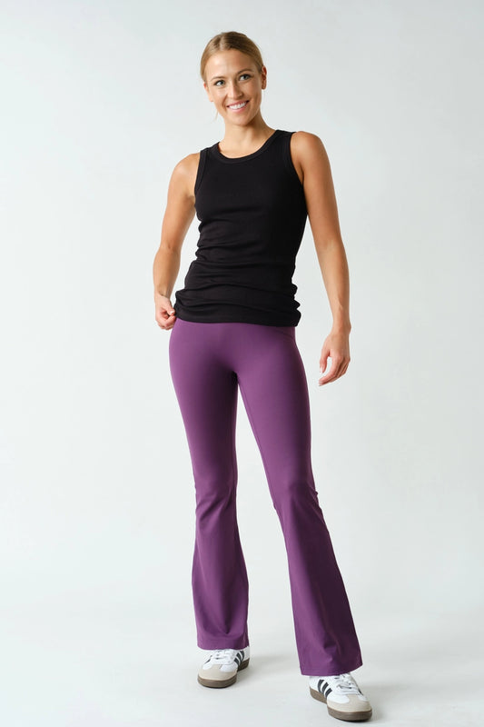 Woman wearing a black tank top and purple pants on a white background