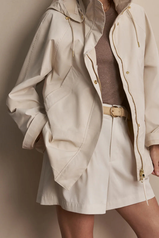 Person wearing a beige raincoat with a plain background
