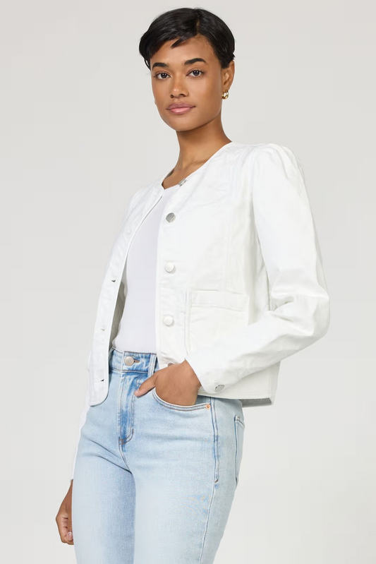 Woman wearing a white denim jacket and light blue jeans on a plain background