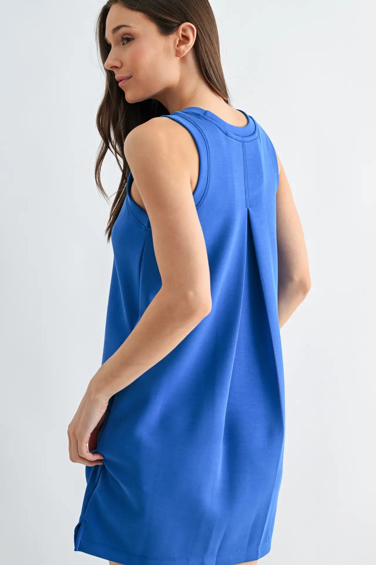 Woman wearing a blue sleeveless dress on a light gray background