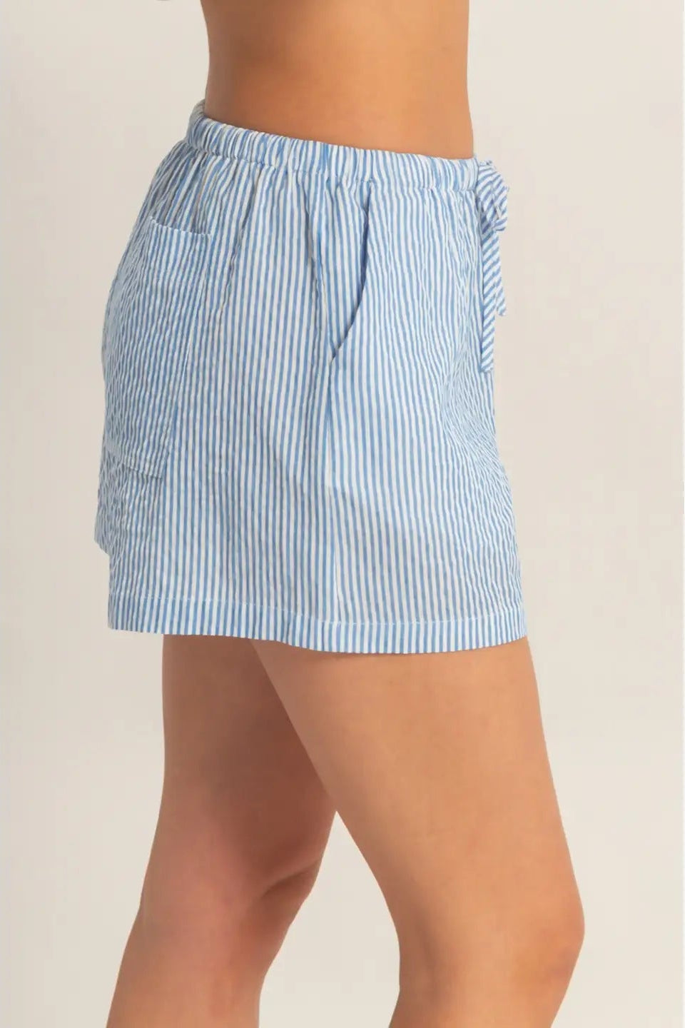 Blue and white striped shorts worn by a person on a beige background