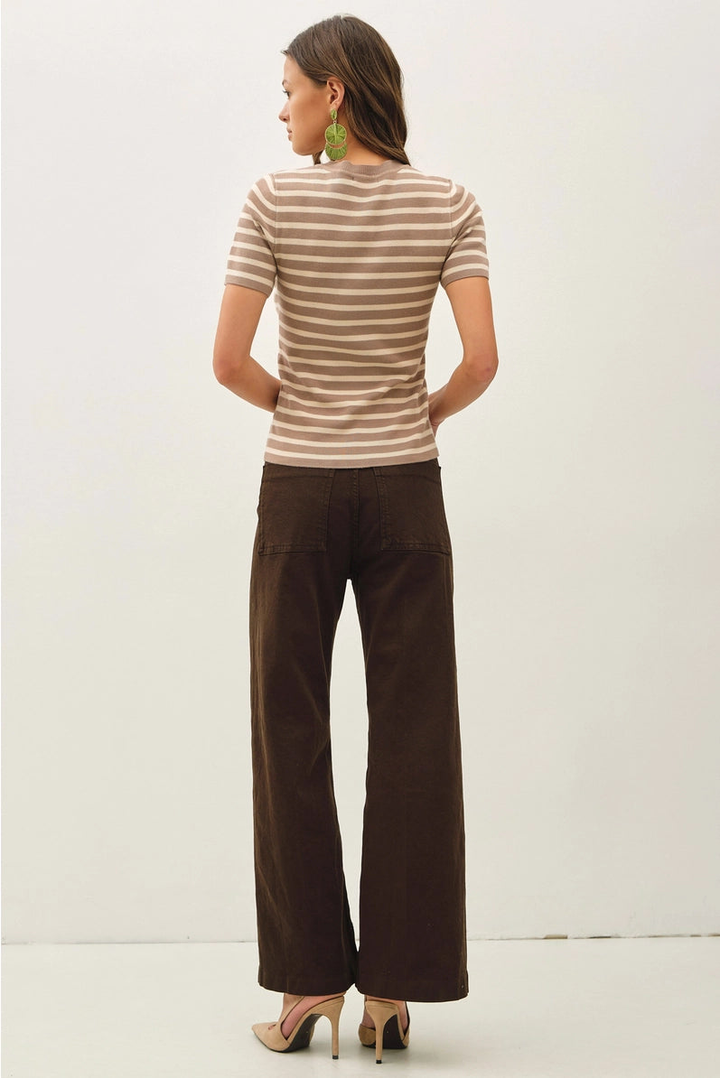 Woman wearing a striped shirt and brown pants on a white background