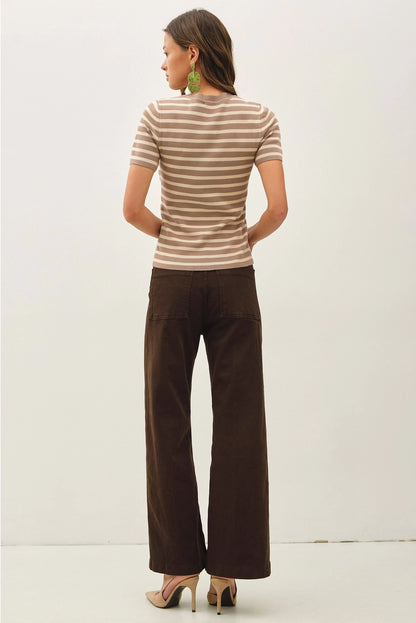 Woman wearing a striped shirt and brown pants on a white background