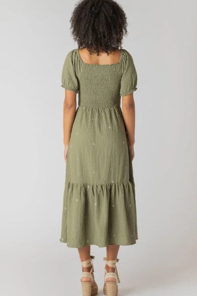 Woman wearing a green dress with a white polka dot pattern on a plain background