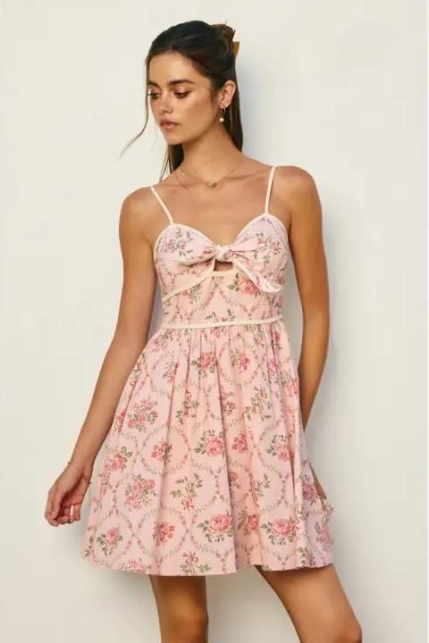 Woman wearing a pink floral dress against a plain background