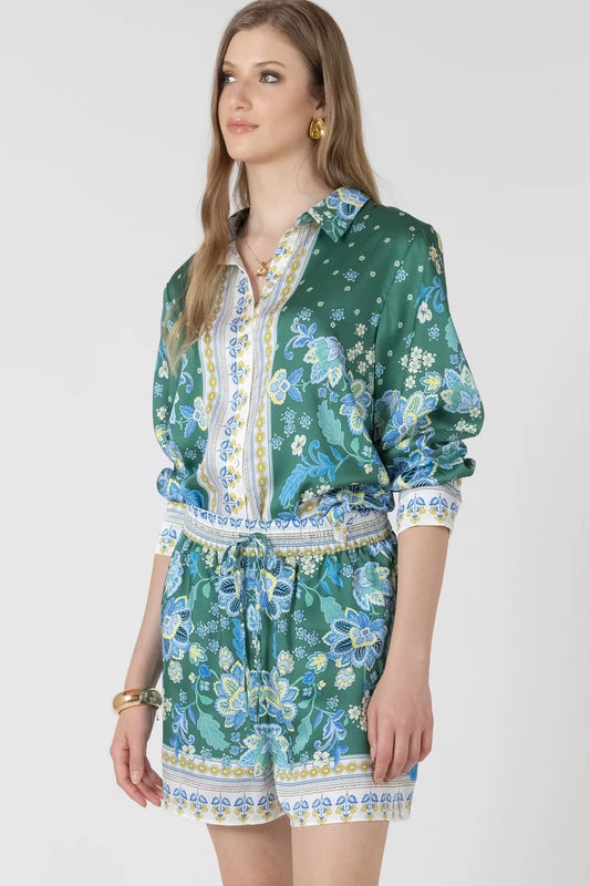 Woman wearing a green floral dress with a white collar on a white background