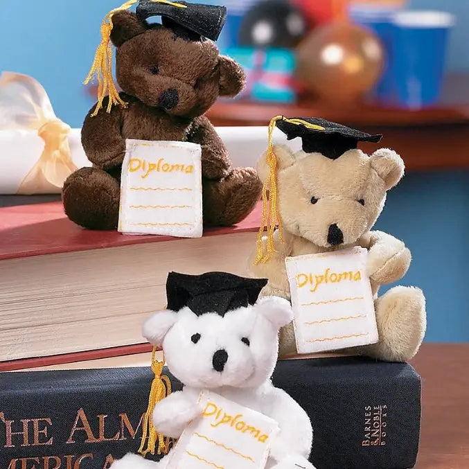 Three teddy bears wearing graduation caps and holding 'diploma' signs on books.
