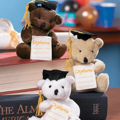 Three teddy bears wearing graduation caps and holding 'diploma' signs on books.