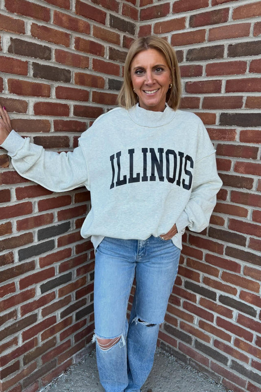 Woman wearing a 'ILLINOIS' sweatshirt against a brick wall
