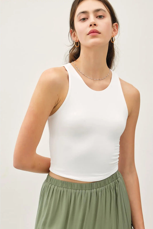 Woman wearing a white tank top and green skirt on a light background