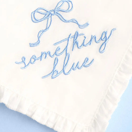 Embroidered text 'Something Blue' on a white fabric background with a blue bow.