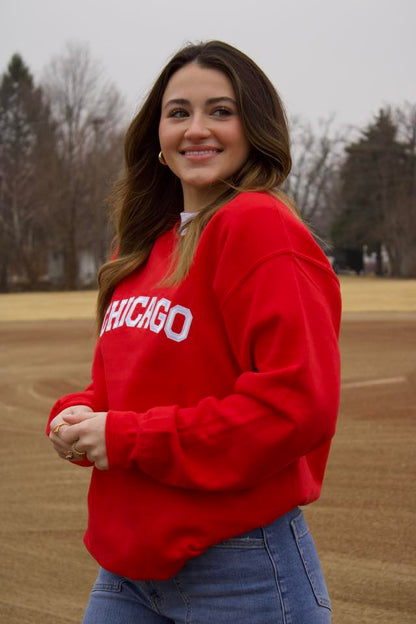 Woman wearing a red 'Chicago' sweatshirt standing on a field.
