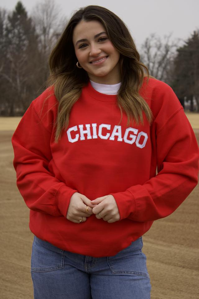 Person wearing a red 'Chicago' sweatshirt in an outdoor setting